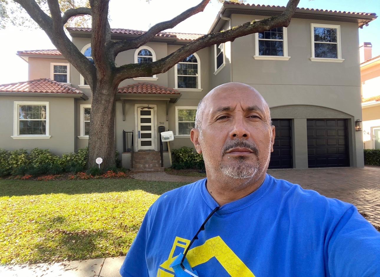 Ecuaconstruction Corp owner John Granda on-site in front of completed two-story luxury estate painting project in Land O' Lakes FL