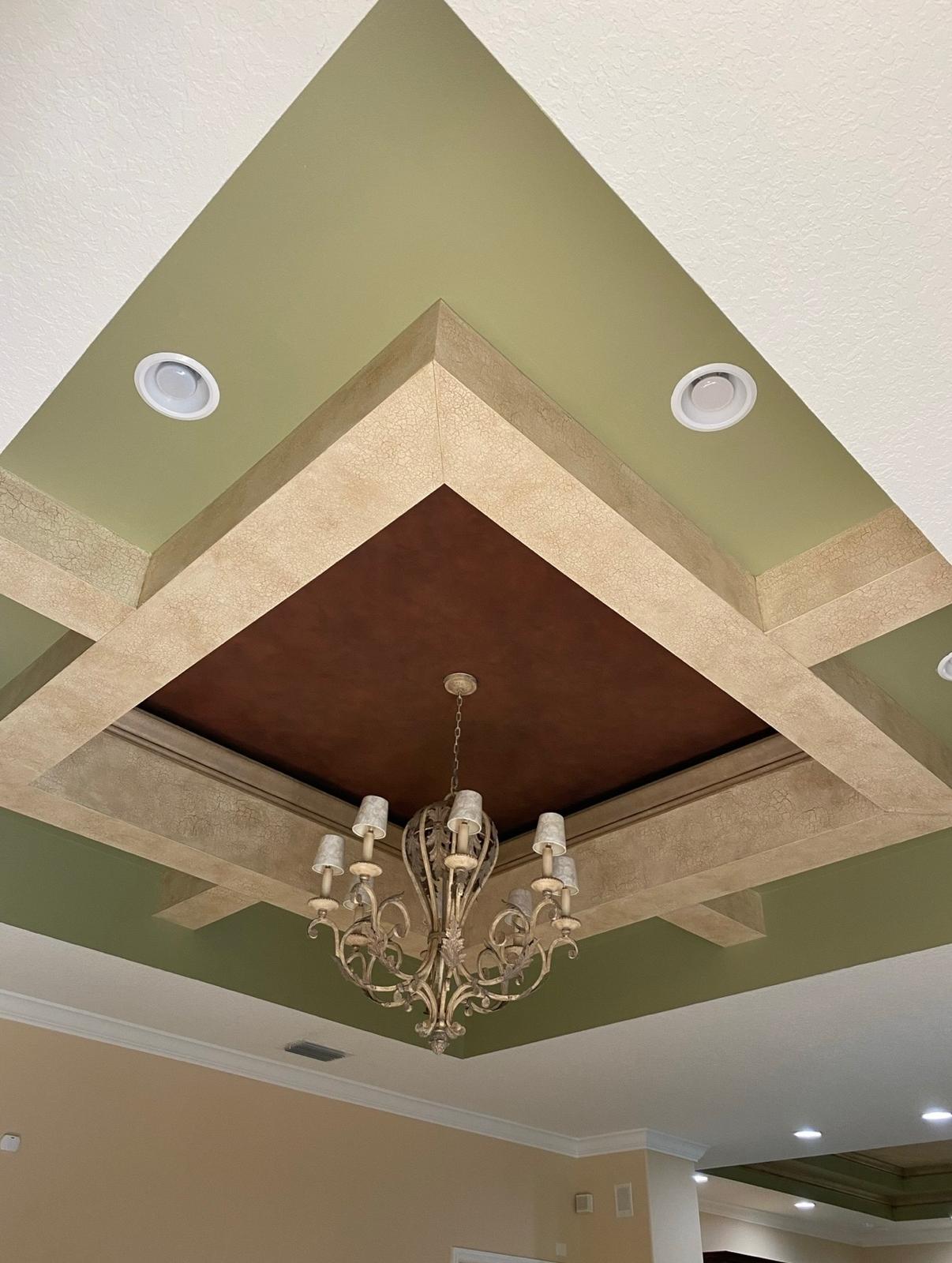Multi-tier custom tray ceiling with aged parchment crackle texture, warm bronze center accent, and ornate chandelier in Odessa FL