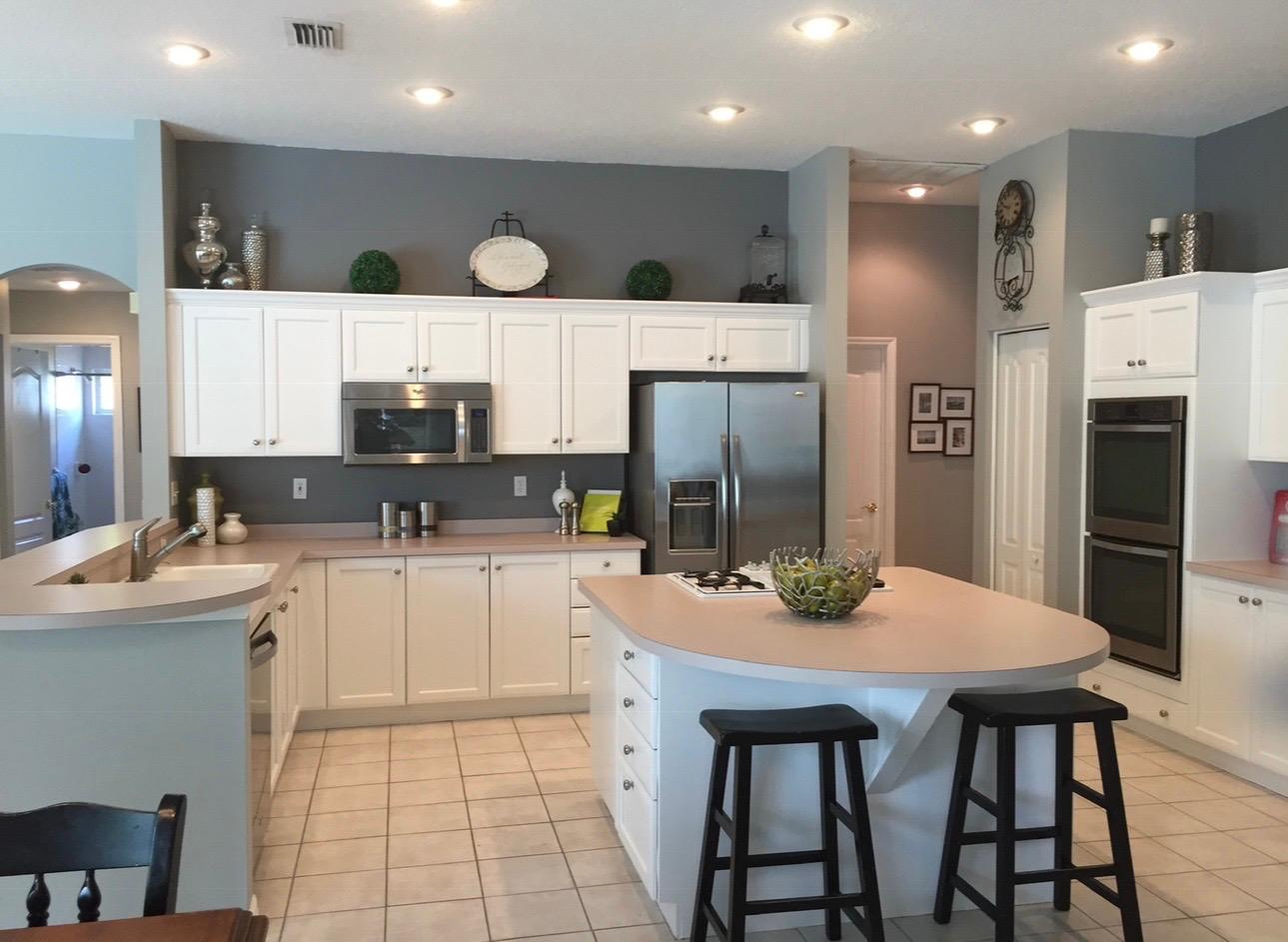 Large open kitchen with bright white painted cabinetry, curved center breakfast island, and recessed lighting in Land O' Lakes FL