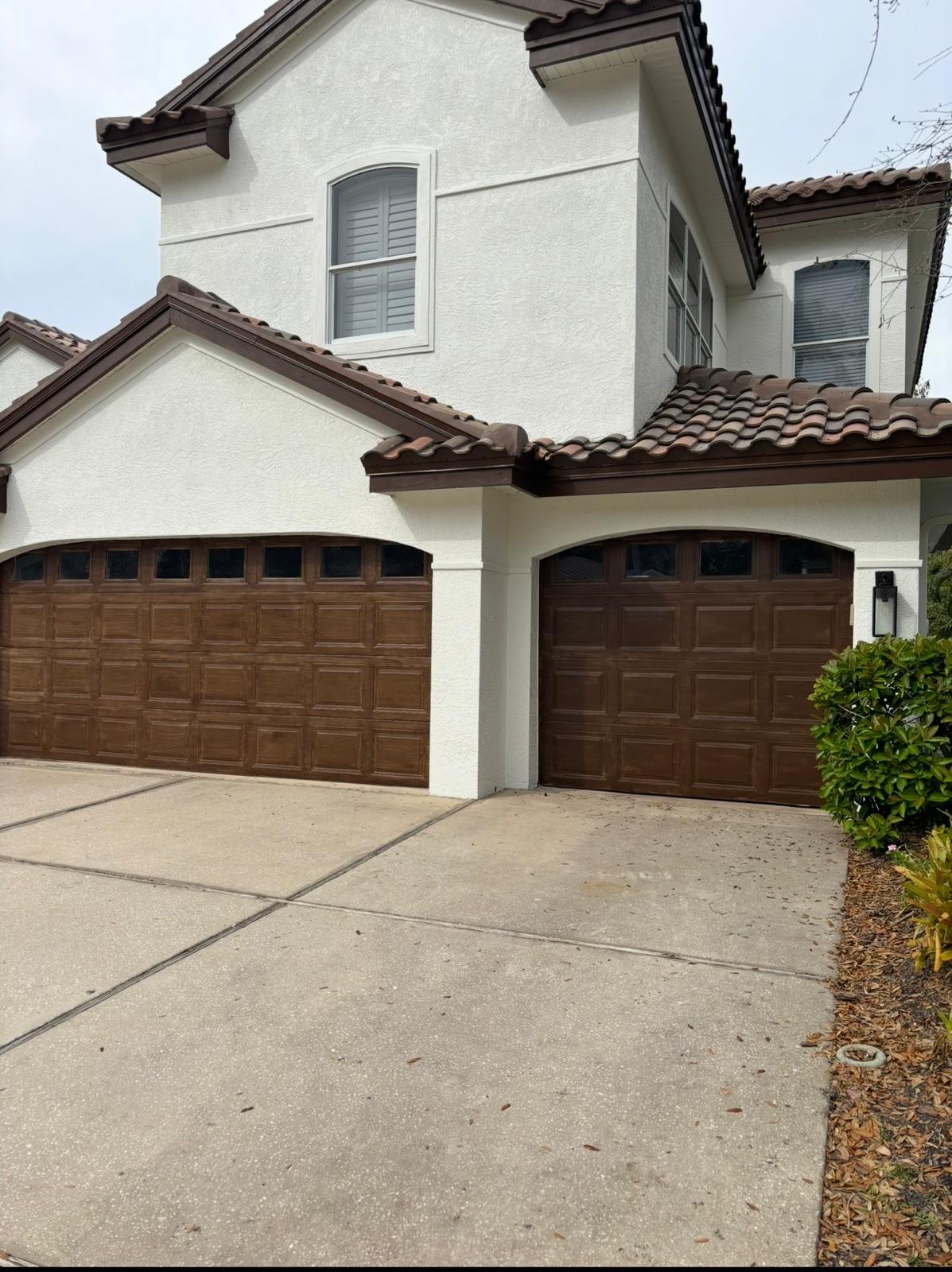 Spanish tile exterior stucco painting and rich walnut stained arched garage doors in Trinity FL