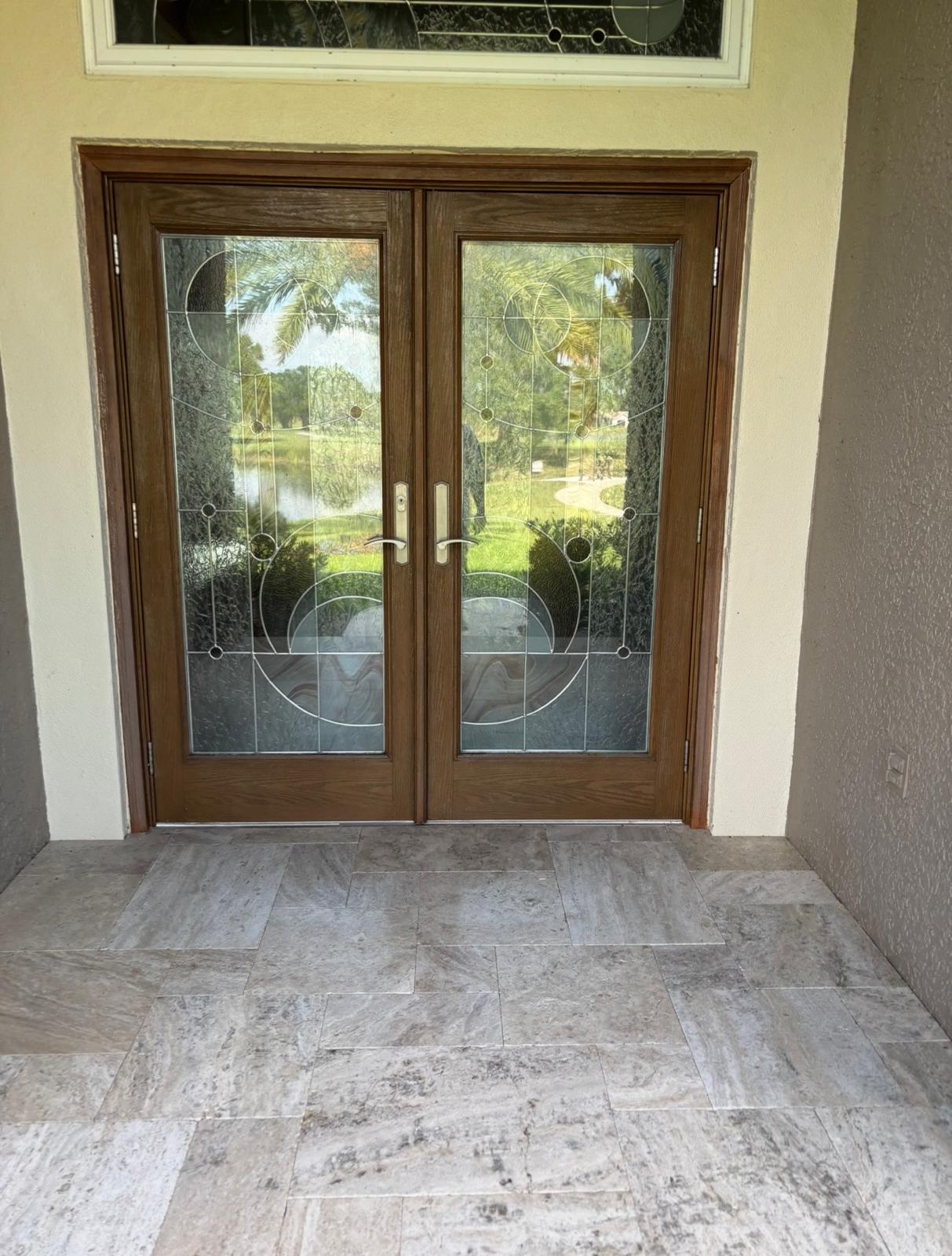 Custom stained double glass entry doors with decorative panels and stone porch in Land O' Lakes FL