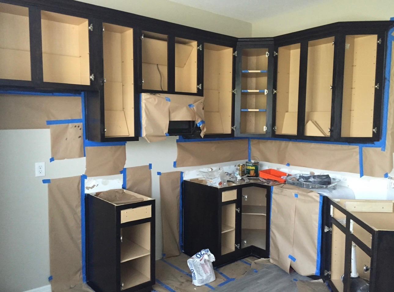 Full room paper masking and dark espresso kitchen cabinet frame spray painting in progress in Tampa FL