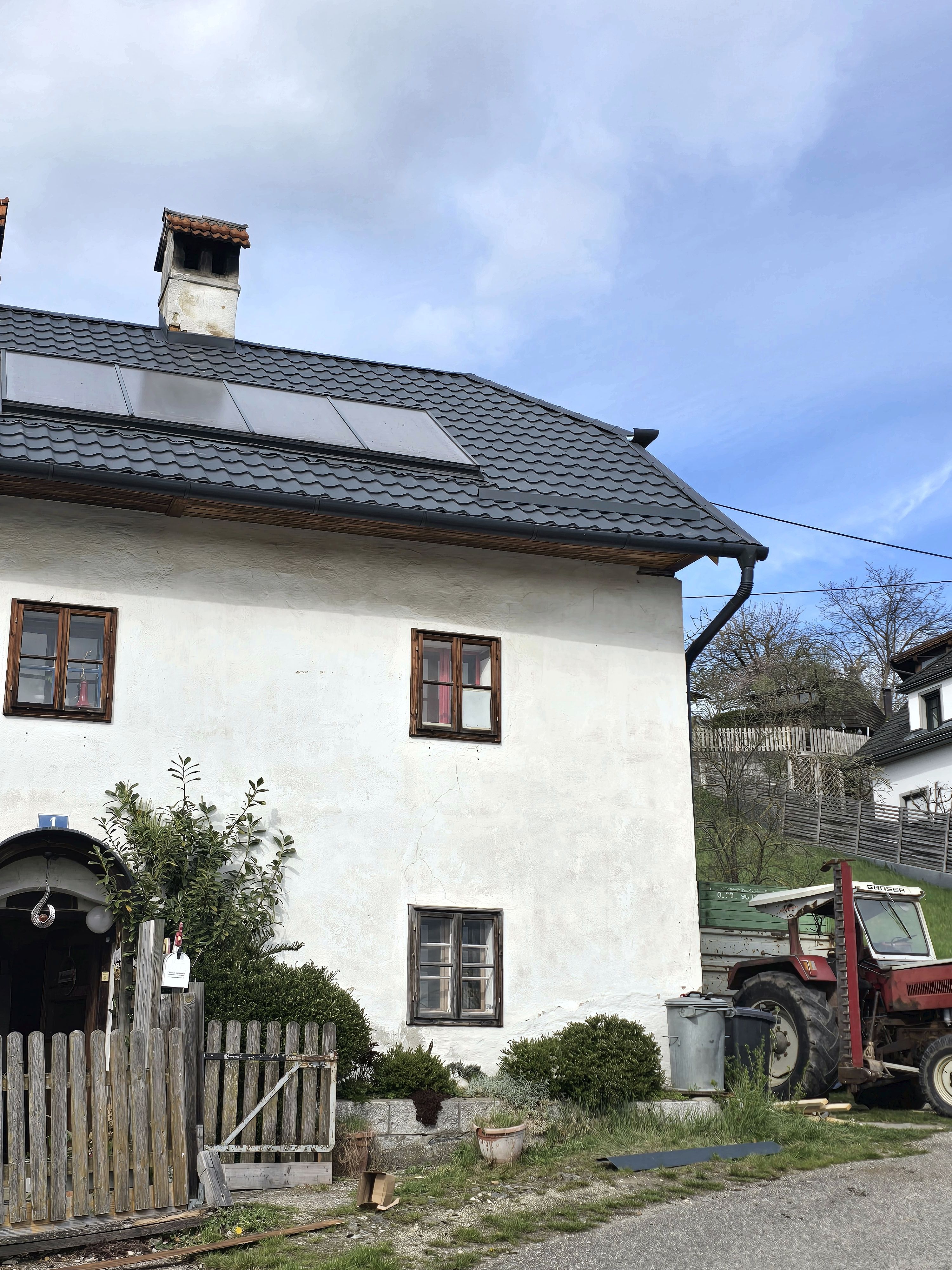 Wohnhaus mit neuem anthrazitfarbenem Metalldach, Solarpaneelen und Entwässerungssystem