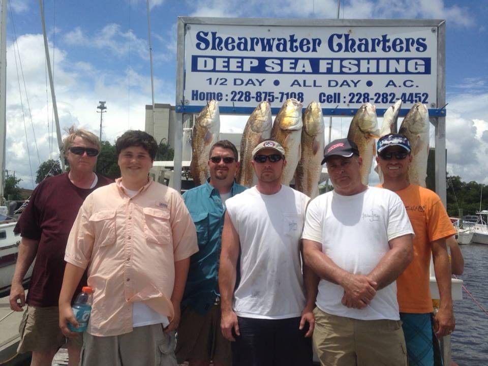 Group of six anglers with redfish at the Shearwater Charters sign in Biloxi