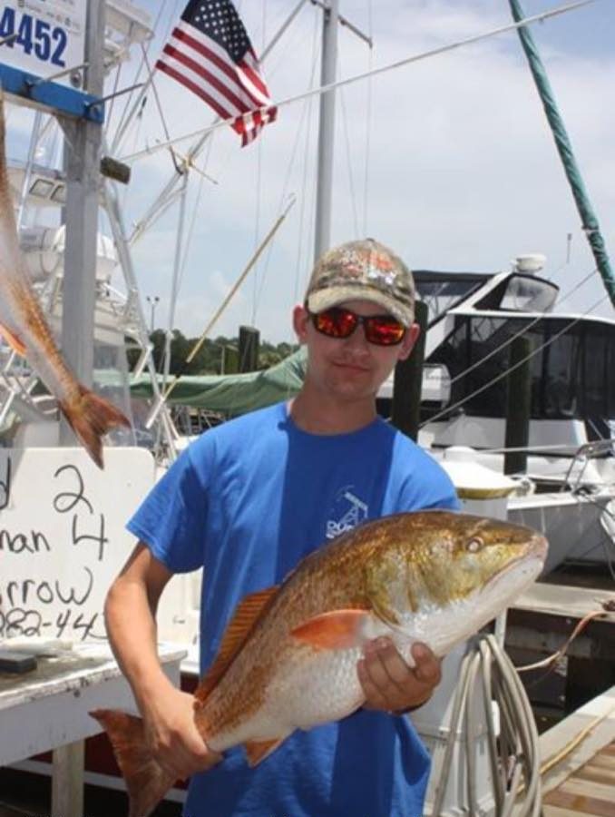 Young angler holding a redfish at Biloxi Small Craft Harbor in Mississippi