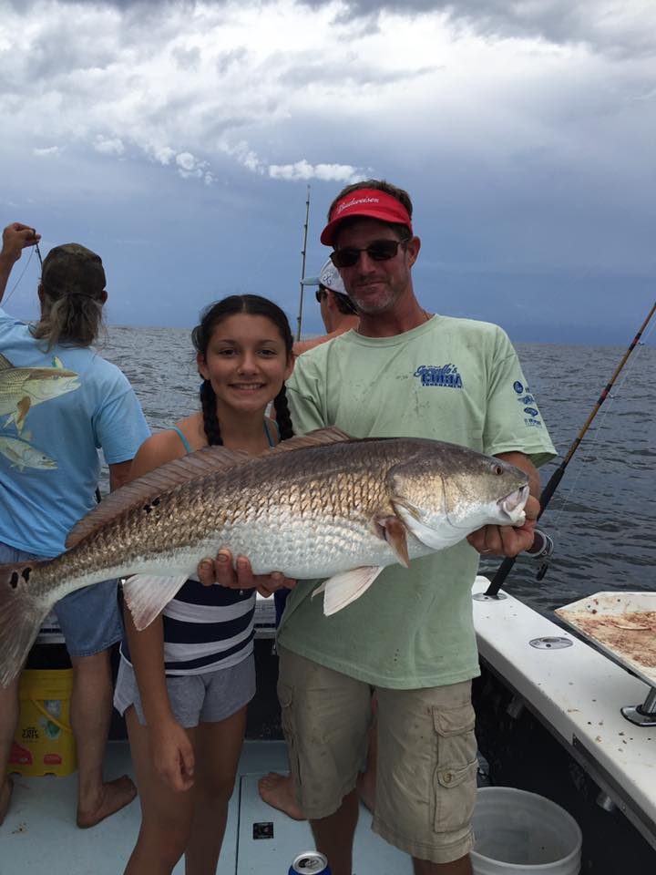 Girl and her dad holding a bull redfish on a half-day fishing trip near Biloxi, MS