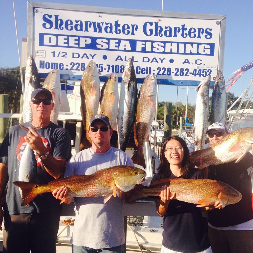 Group of friends with a mixed catch at the Shearwater Charters sign in Biloxi