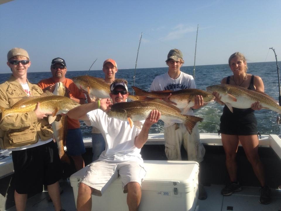 Group of anglers holding bull redfish offshore on an 8-hour full-day fishing charter from Biloxi