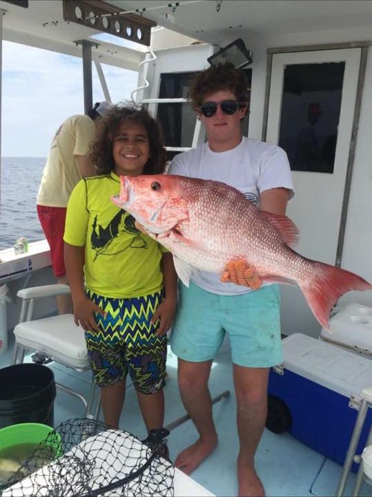 Two young anglers holding a red snapper on a family fishing trip aboard the Shearwater