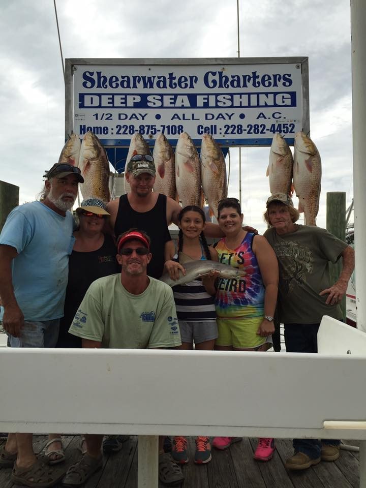 Family with a shark and redfish catch at the Shearwater Charters sign in Biloxi