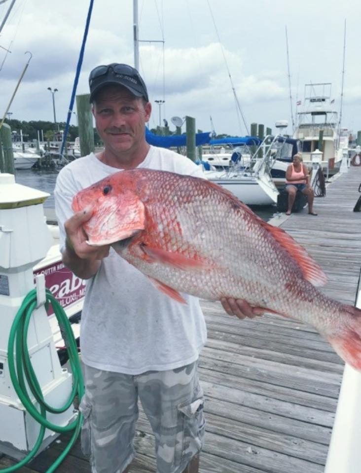 Angler holding a large red snapper on the dock at Biloxi Small Craft Harbor