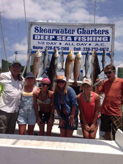 Anglers holding redfish in front of the Shearwater Charters sign after a 6-hour fishing charter in Biloxi