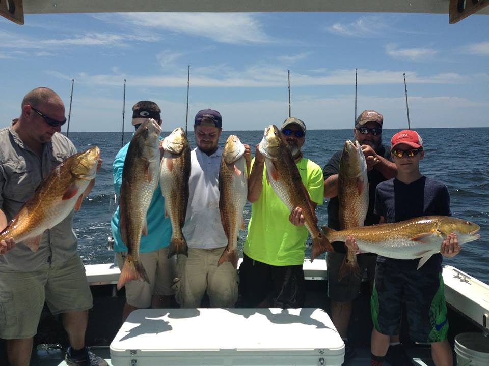 Group of anglers holding bull redfish in the Gulf of Mexico aboard the Shearwater