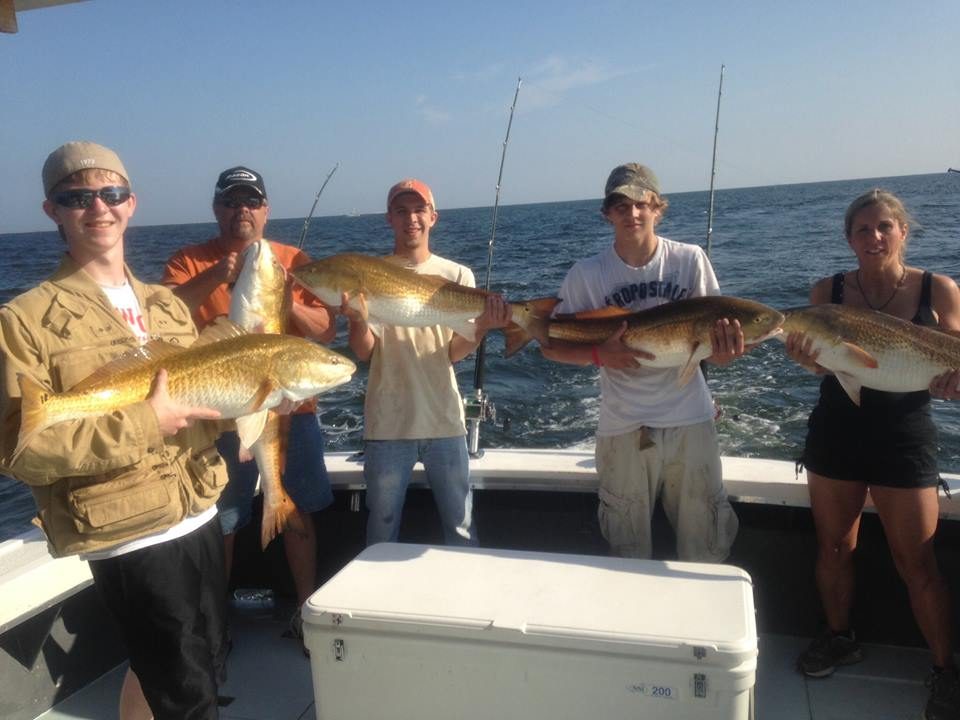 Group of anglers holding bull redfish on a Biloxi deep sea fishing charter