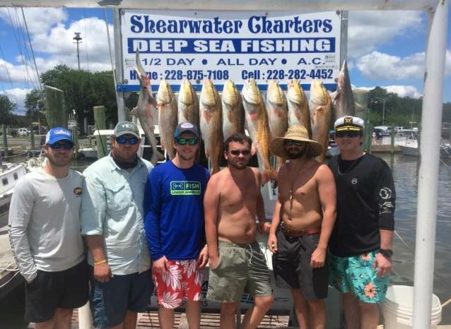Group of seven anglers with redfish at the Shearwater Charters sign in Biloxi