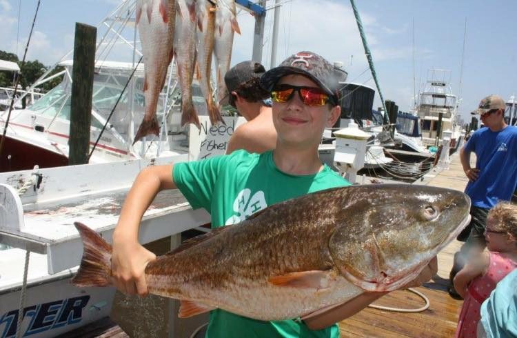 Young angler holding a bull redfish at the dock after a half-day fishing charter in Biloxi