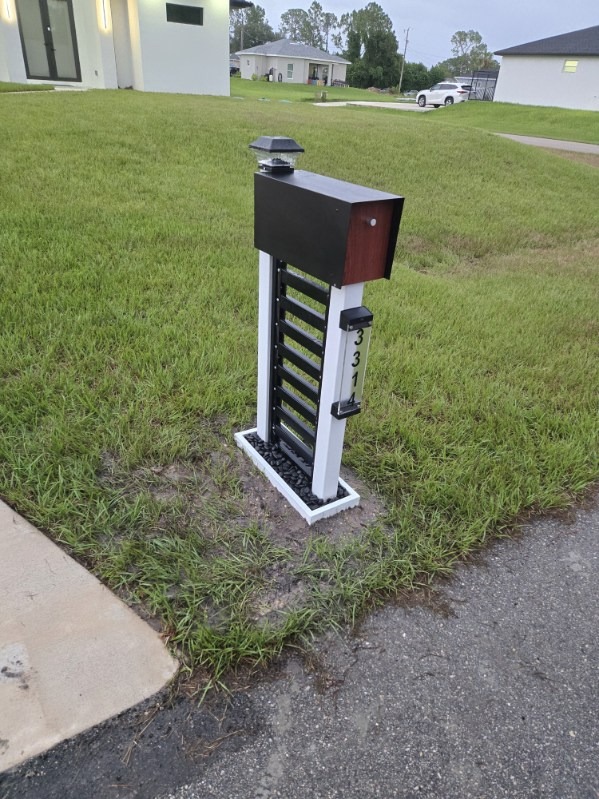 Two-tone custom aluminum mailbox post with black horizontal slats and white upright frame with solar post light
