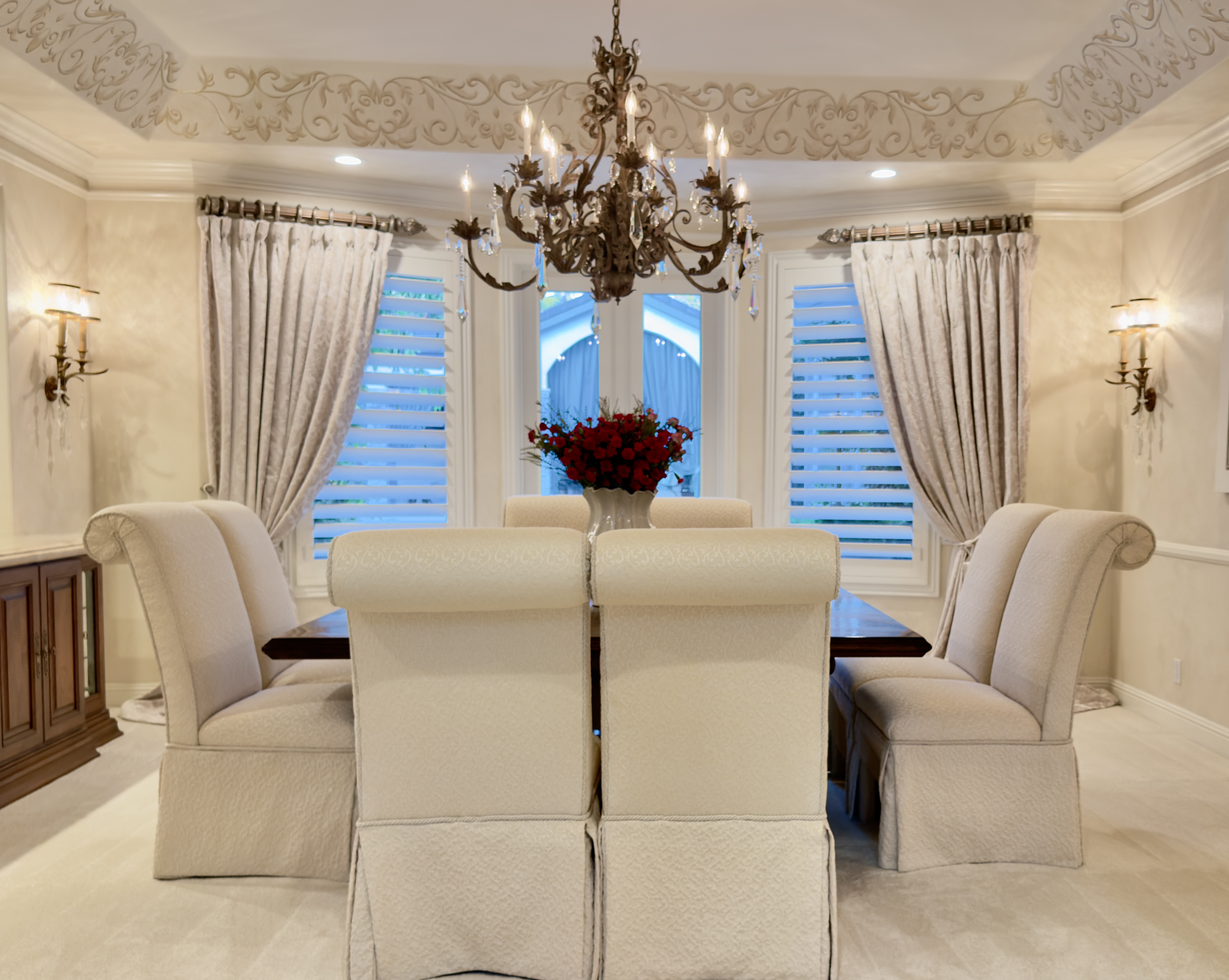 Formal dining room with custom tailored draperies, plantation shutters, and elegant chandelier
