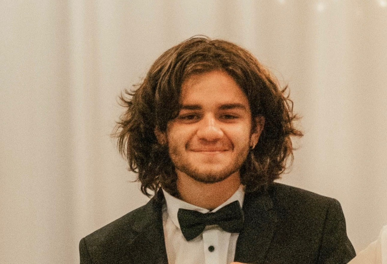 AJ smiling in a tuxedo