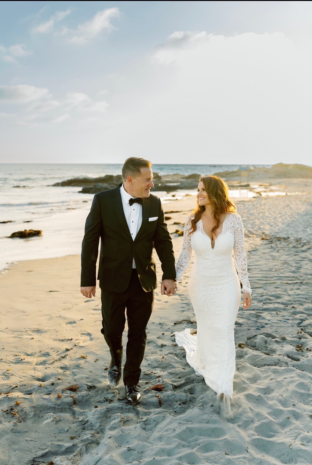 Jay and Melessa walking together on the beach on their wedding day