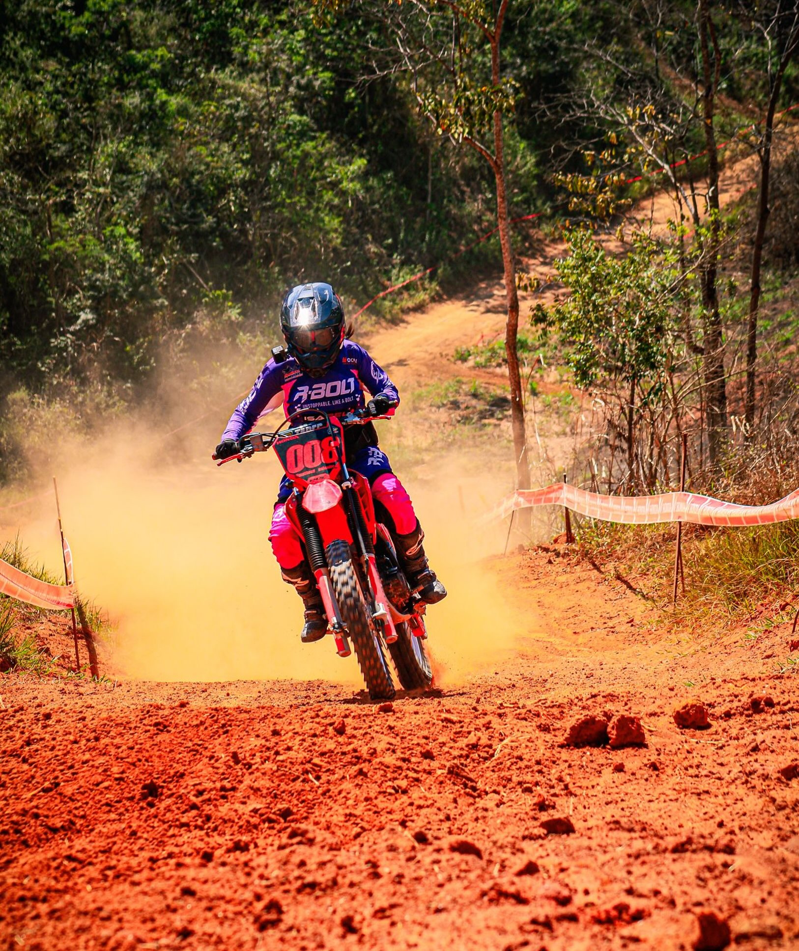 Isabela Tondim acelerando na curva de terra vermelha com equipamento de moto