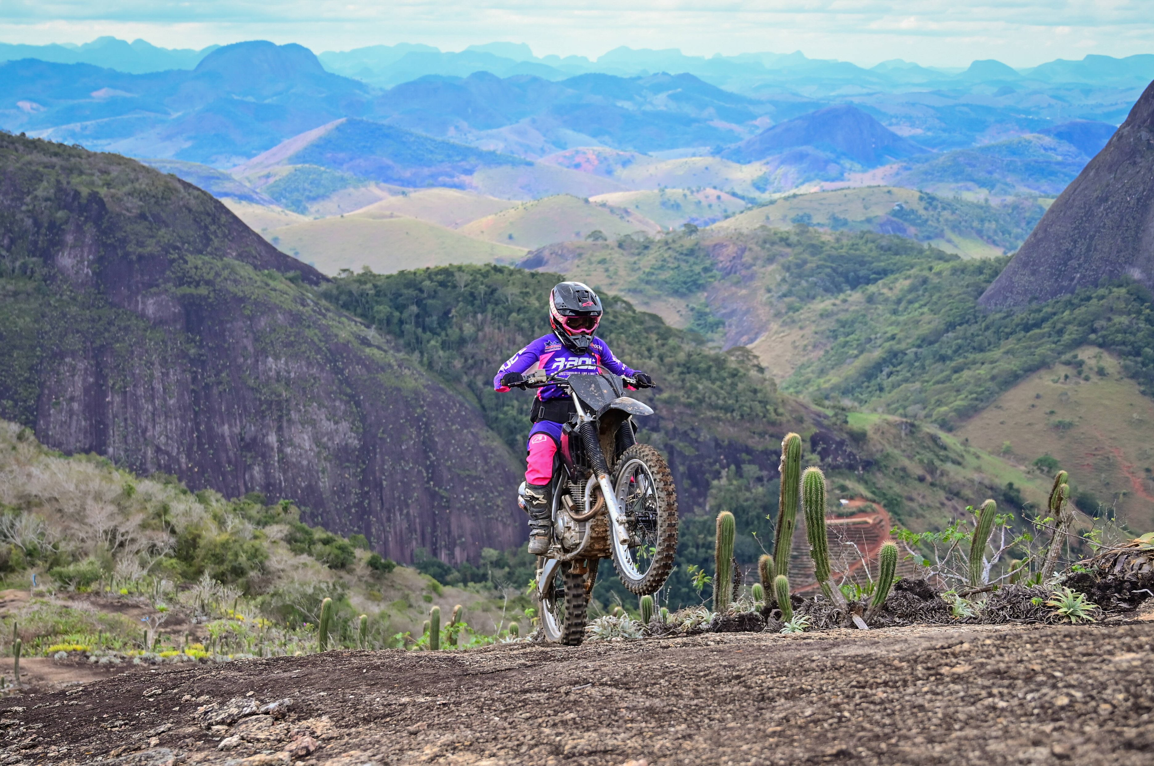Isabela Tondim acelerando sua moto em manobra radical no topo do morro em Minas Gerais