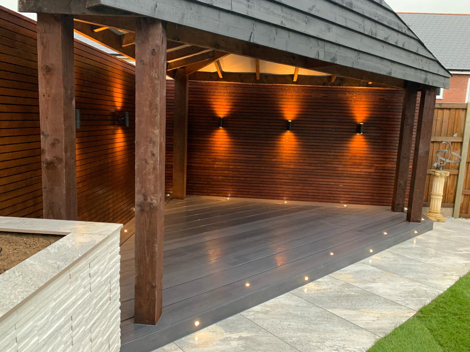 Custom timber sheltered decking structure with integrated lighting and slatted walls in Essex
