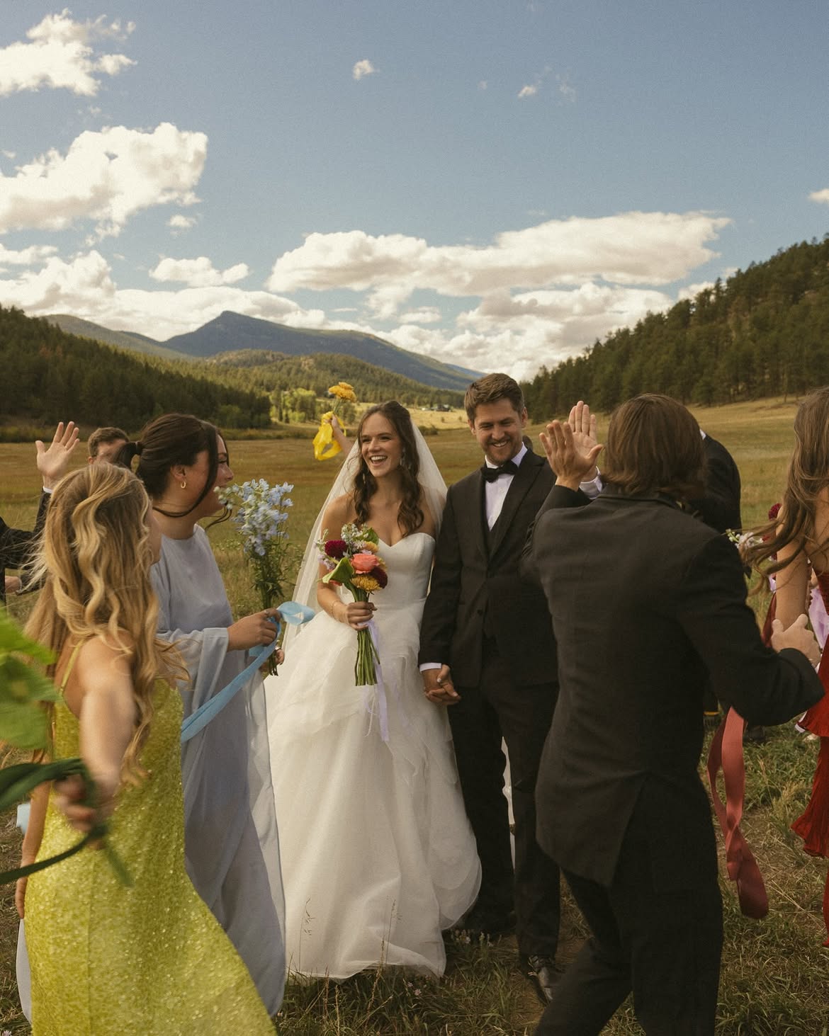 Bride and groom celebrating with high-fives in the mountain meadow at Deer Creek Valley Ranch