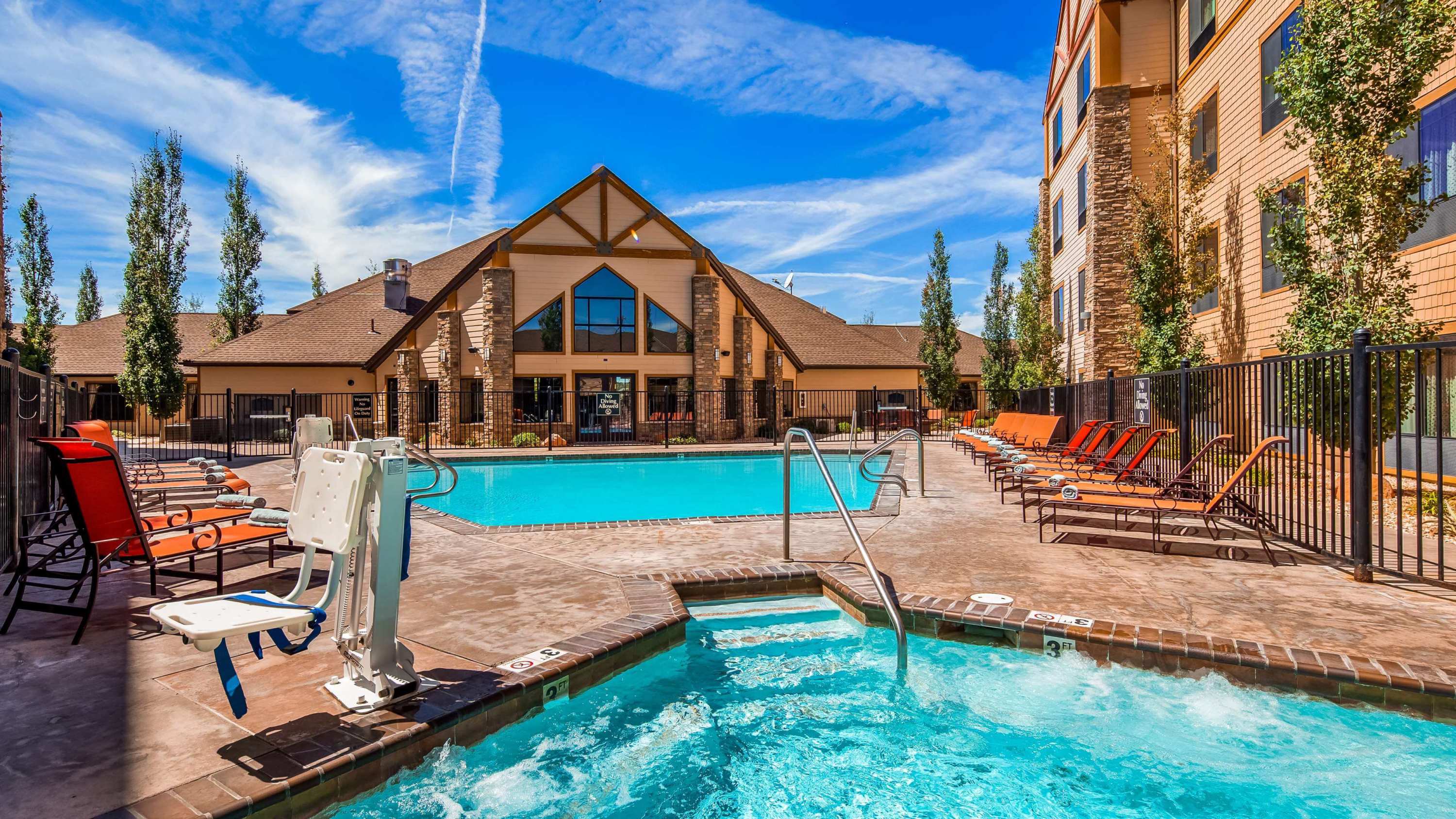 Upscale hotel outdoor pool and spa courtyard with lodge architecture and sun loungers