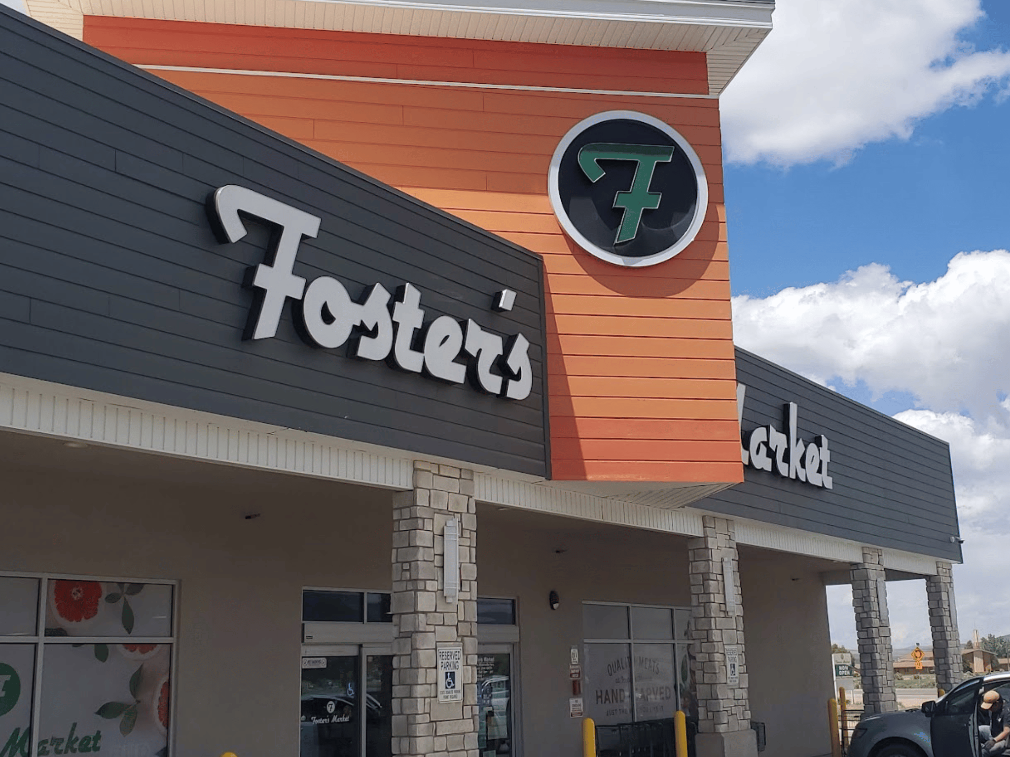 Exterior storefront signage of Foster's Market with modern stone columns and orange siding accents in Enoch, Utah