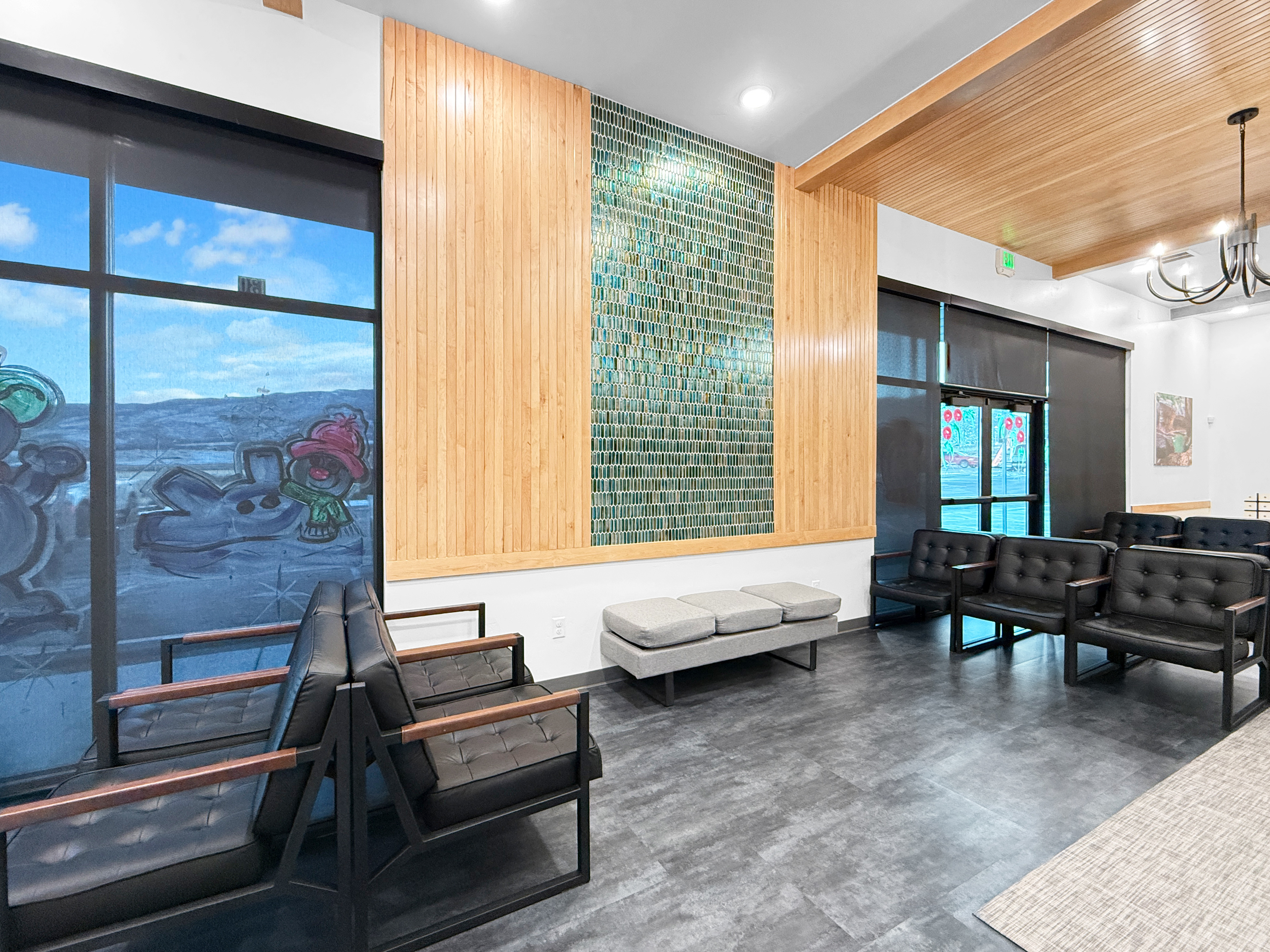 Waiting room feature wall with vertical wood paneling and green mosaic tile accent wall behind bench seating
