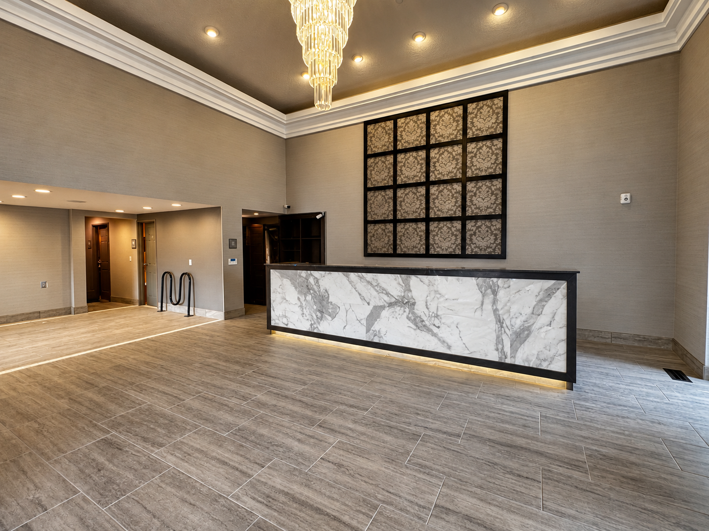Abbey Inn check-in reception desk with illuminated marble frontage, decorative wall panel, and crystal chandelier