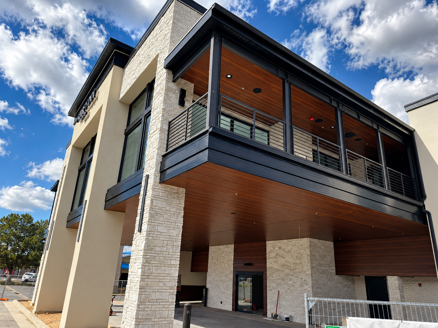 Abbey Inn modern entrance porte-cochere and upper balcony with wood-paneled soffit, stone columns, and black architectural railings