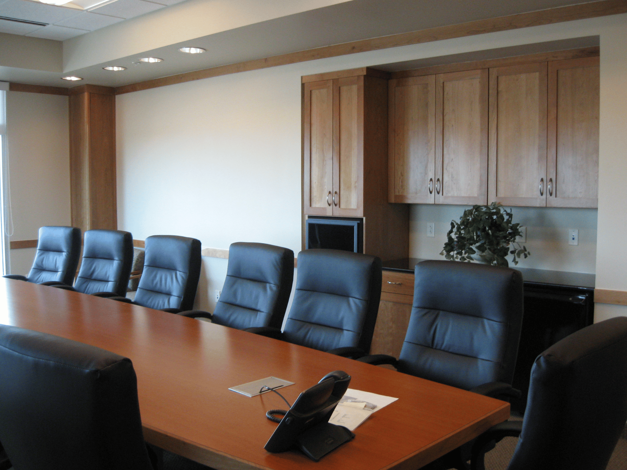 Finished executive conference room with custom wood cabinetry and executive conference table