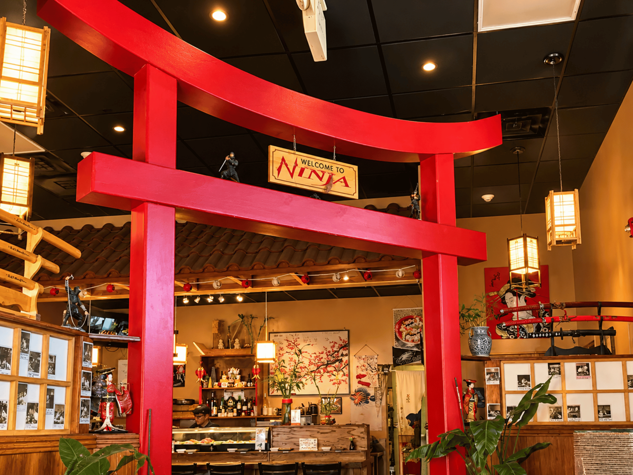 Dramatic red Torii gate entrance with Welcome to Ninja signage, traditional lanterns, and sushi bar in Cedar City, Utah