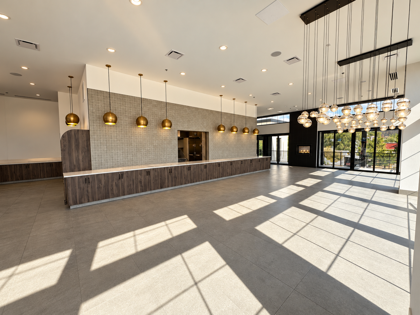 Spacious renovated event and breakfast hall with extended buffet counter, brass globe pendant lighting, and modern globe chandeliers