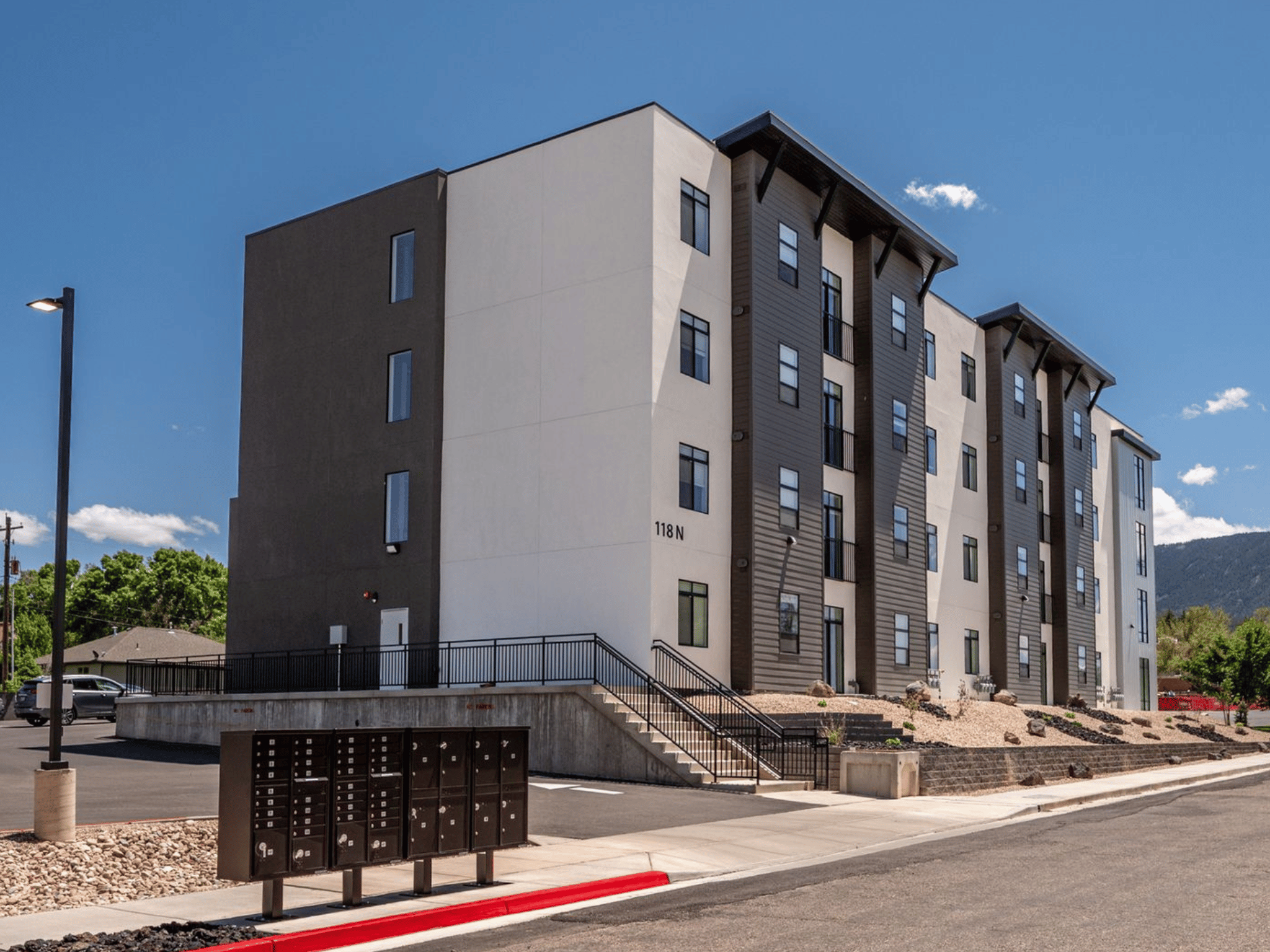 Street-level entrance of Harding Avenue Lofts at 118 N with mailbox kiosks, landscaped entryway, and exterior stairs