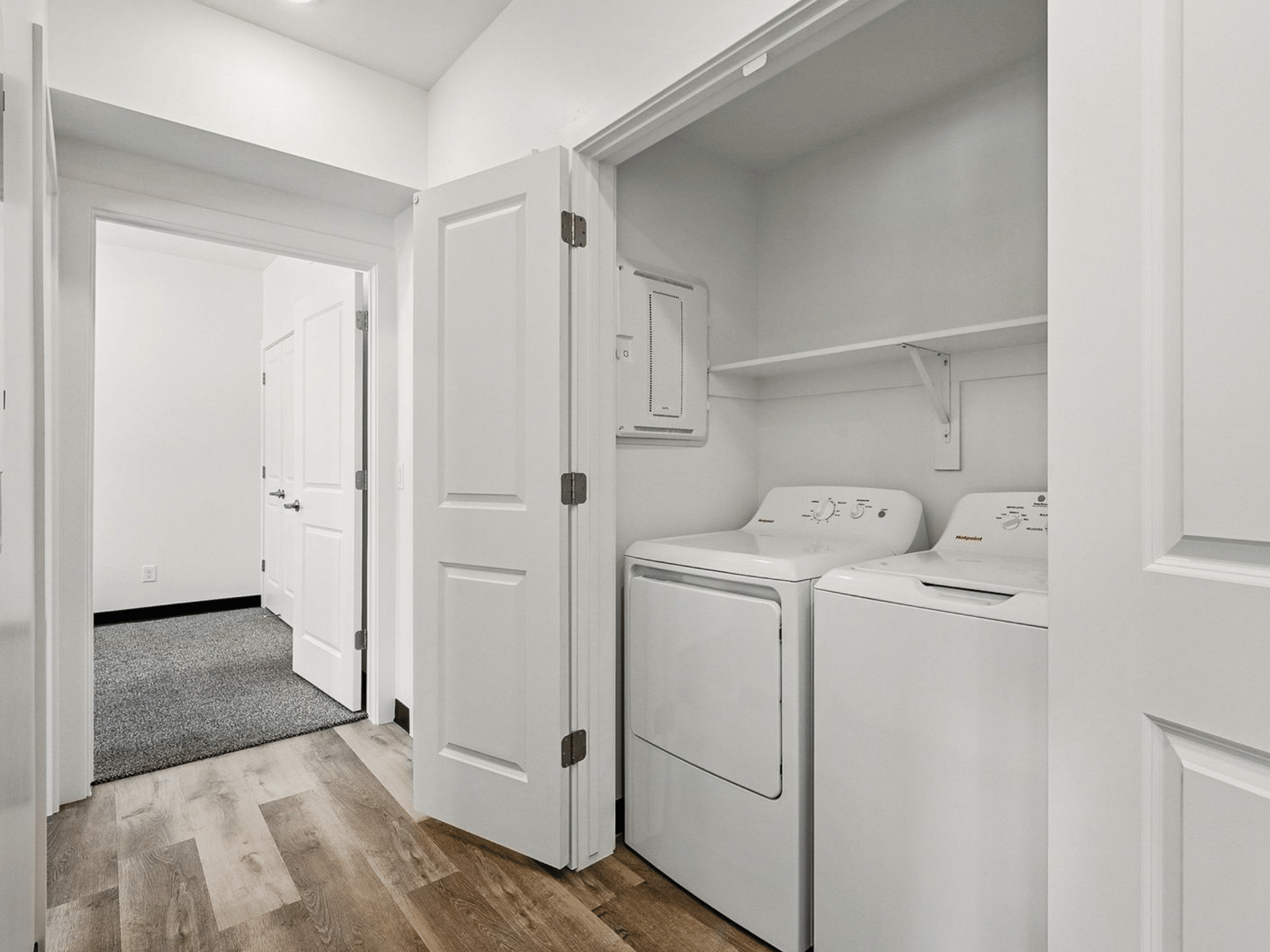 In-unit laundry closet with washer and dryer units and hallway to bedrooms