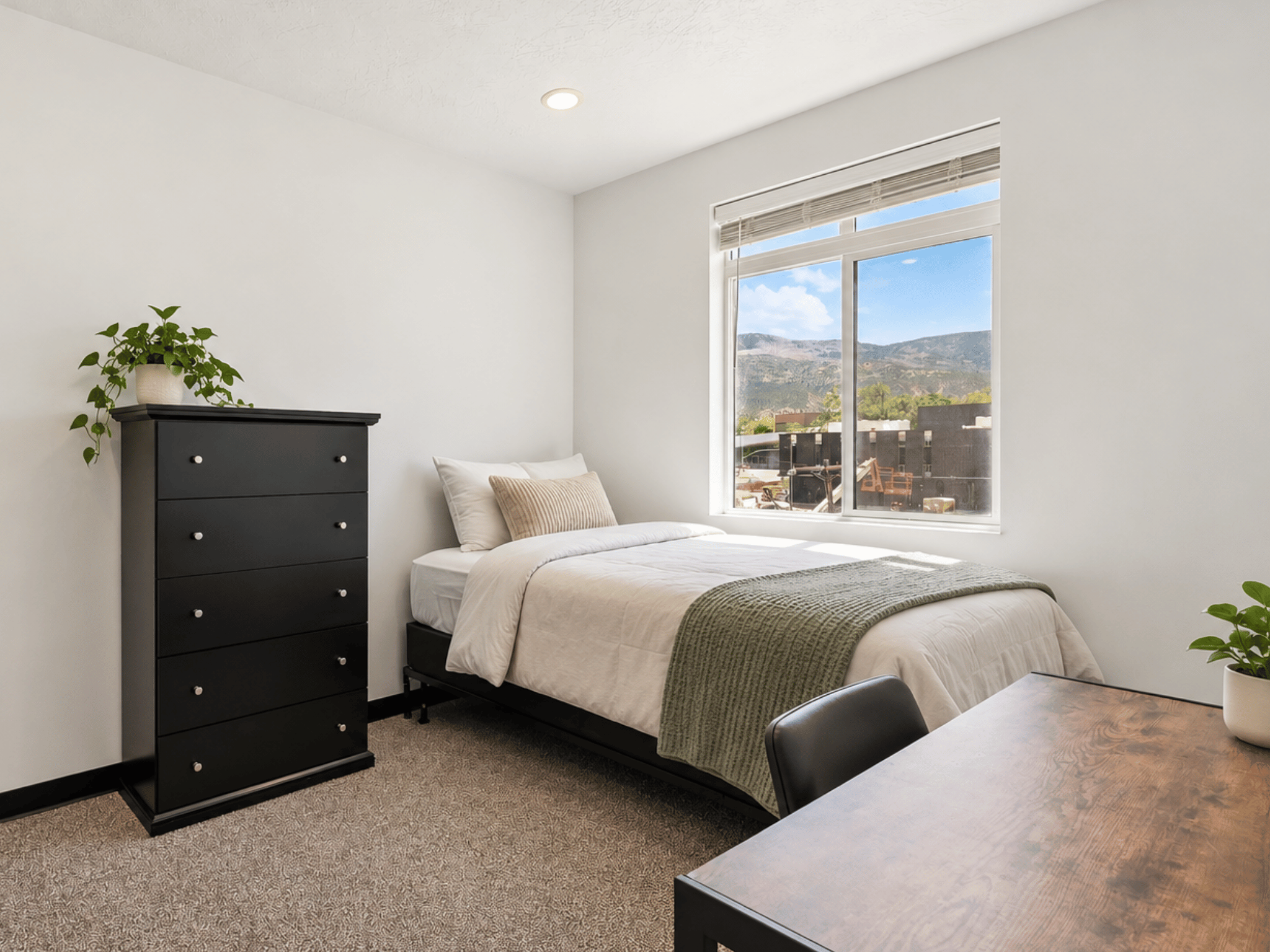Furnished student bedroom with bed, desk, dresser, and scenic mountain views