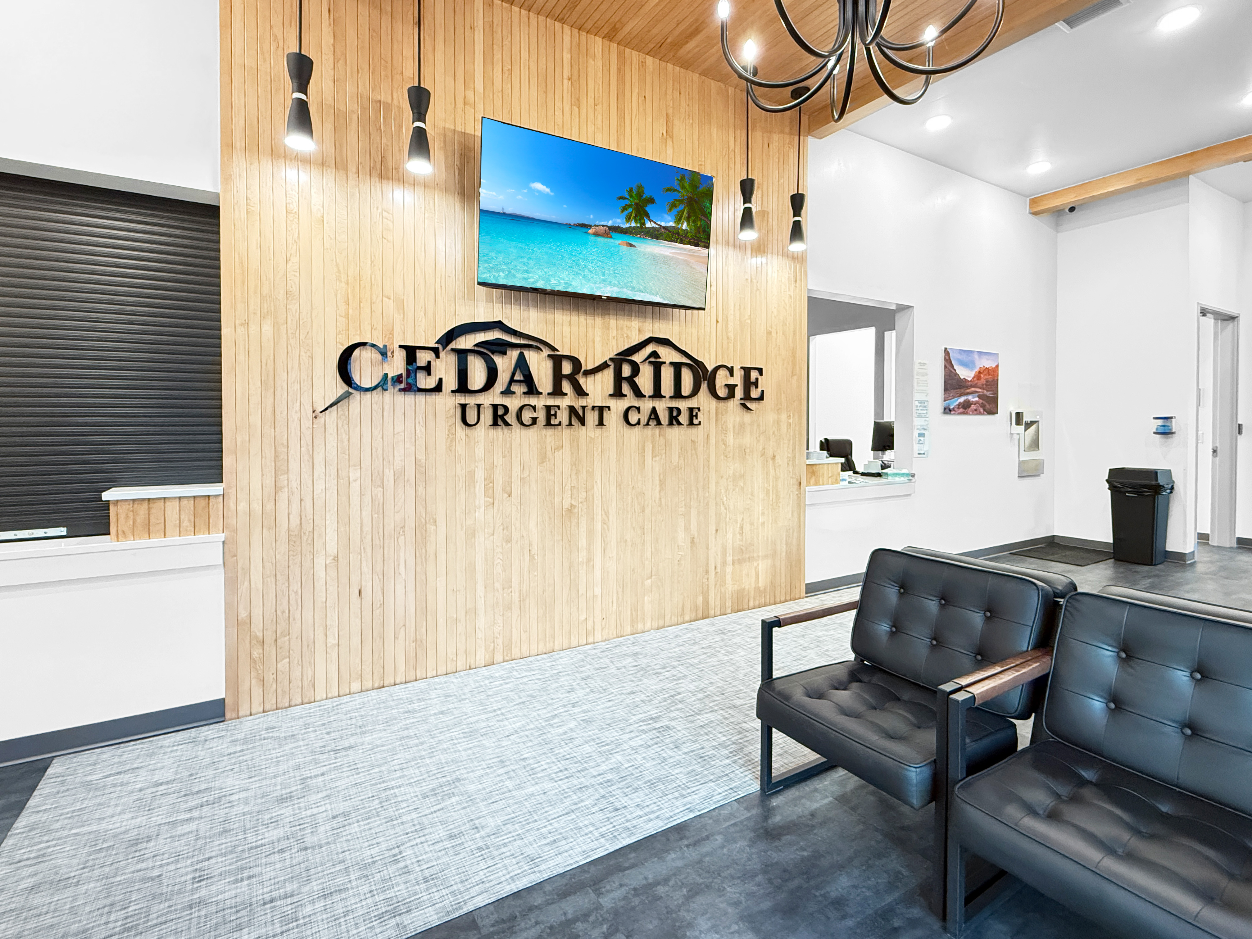 Reception check-in counter and dimensional Cedar Ridge Urgent Care wall sign viewed from the patient waiting area