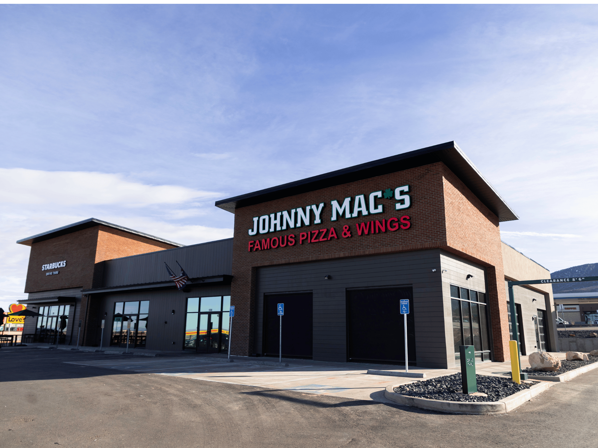 Exterior view of Johnny Mac's Famous Pizza & Wings building and storefront under a clear blue sky