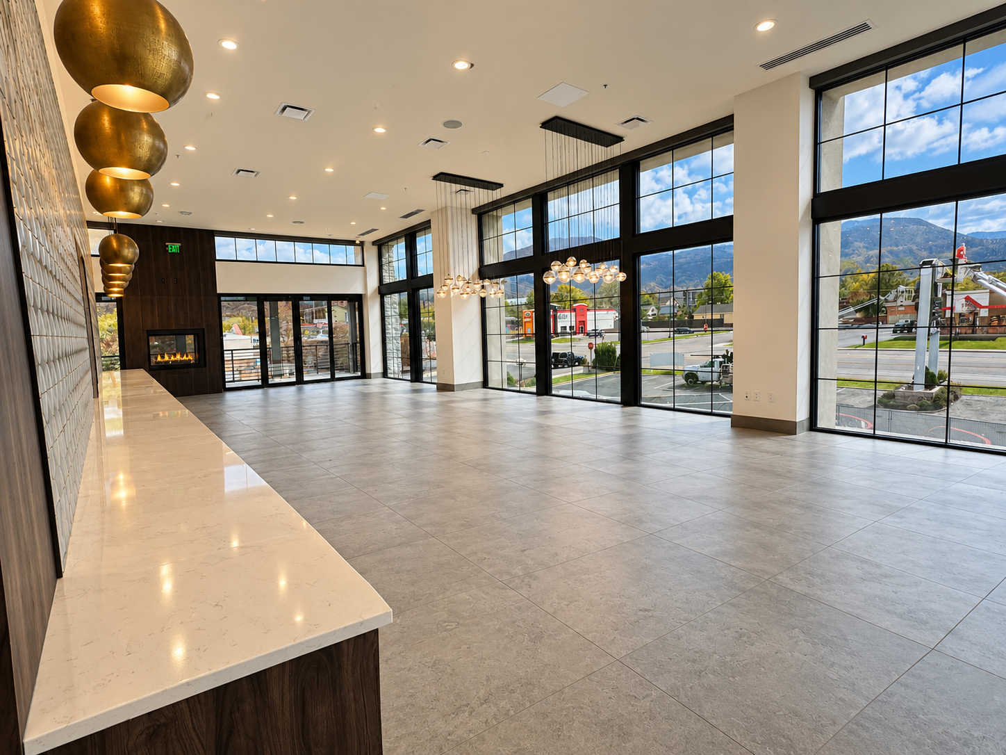 Bright banquet and gathering hall with floor-to-ceiling black-framed windows overlooking the mountains, brass fixtures, and fireplace
