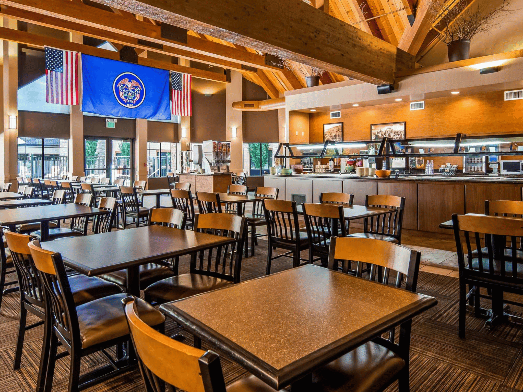 Hotel dining room with exposed wood trusses, breakfast buffet serving line, and rustic wood dining tables