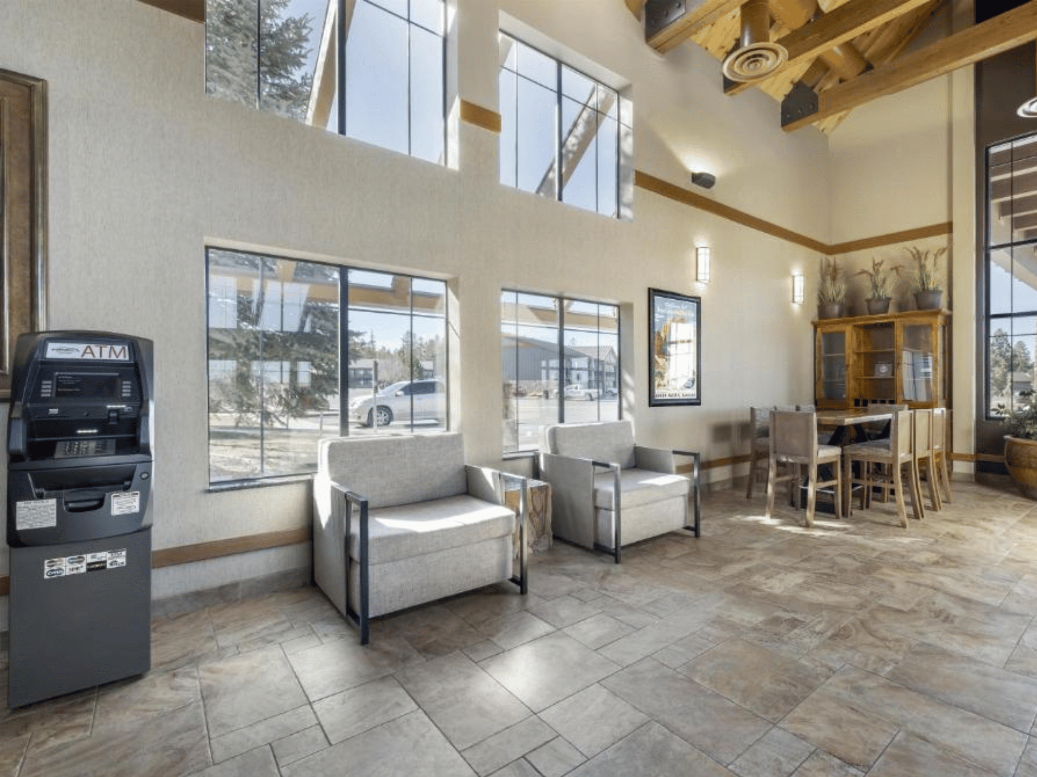 Lobby lounge seating area with vaulted clerestory windows, natural stone tile flooring, and timber framing