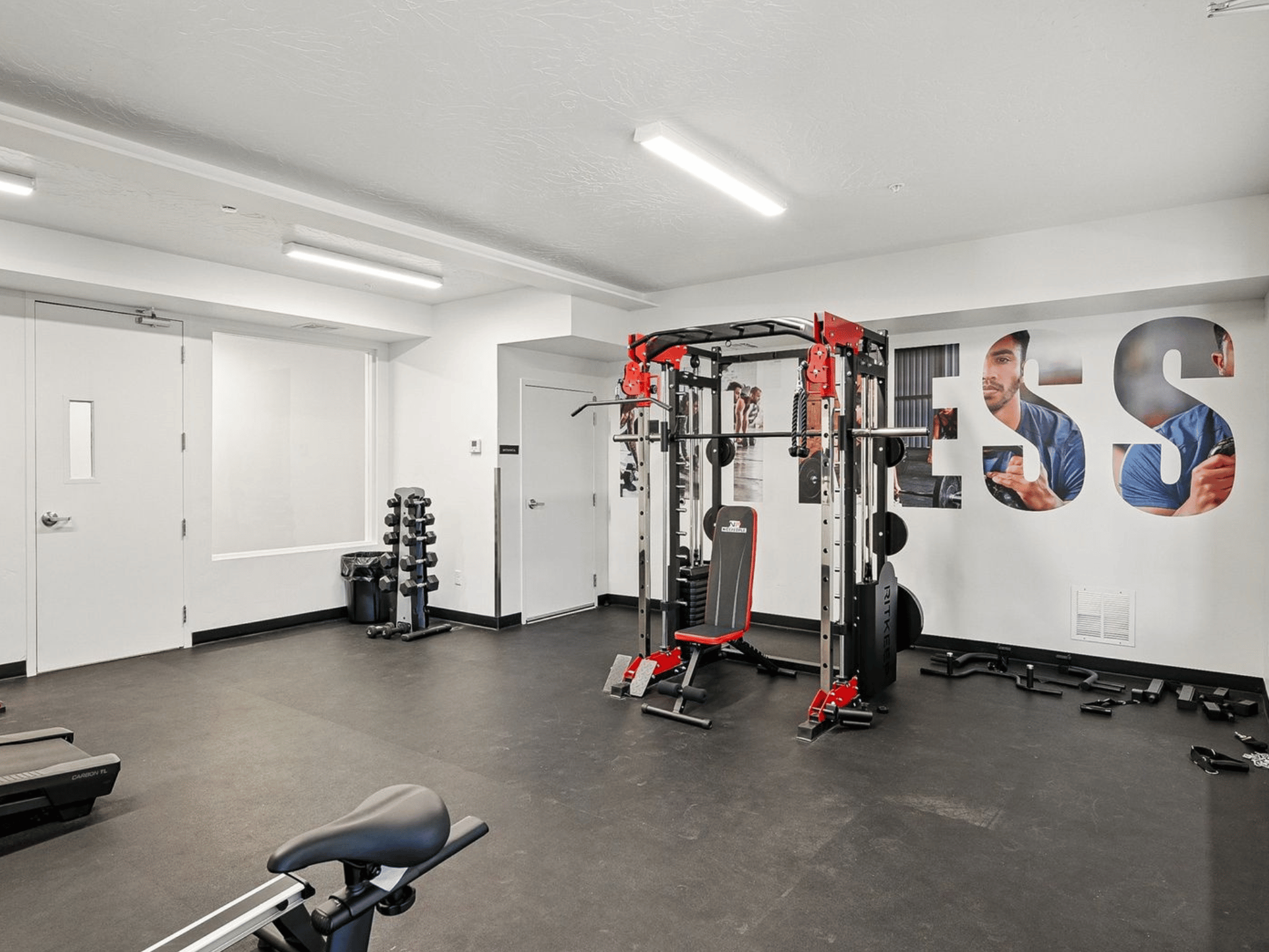 Resident fitness center with strength training rack, free weights, and athletic wall graphics