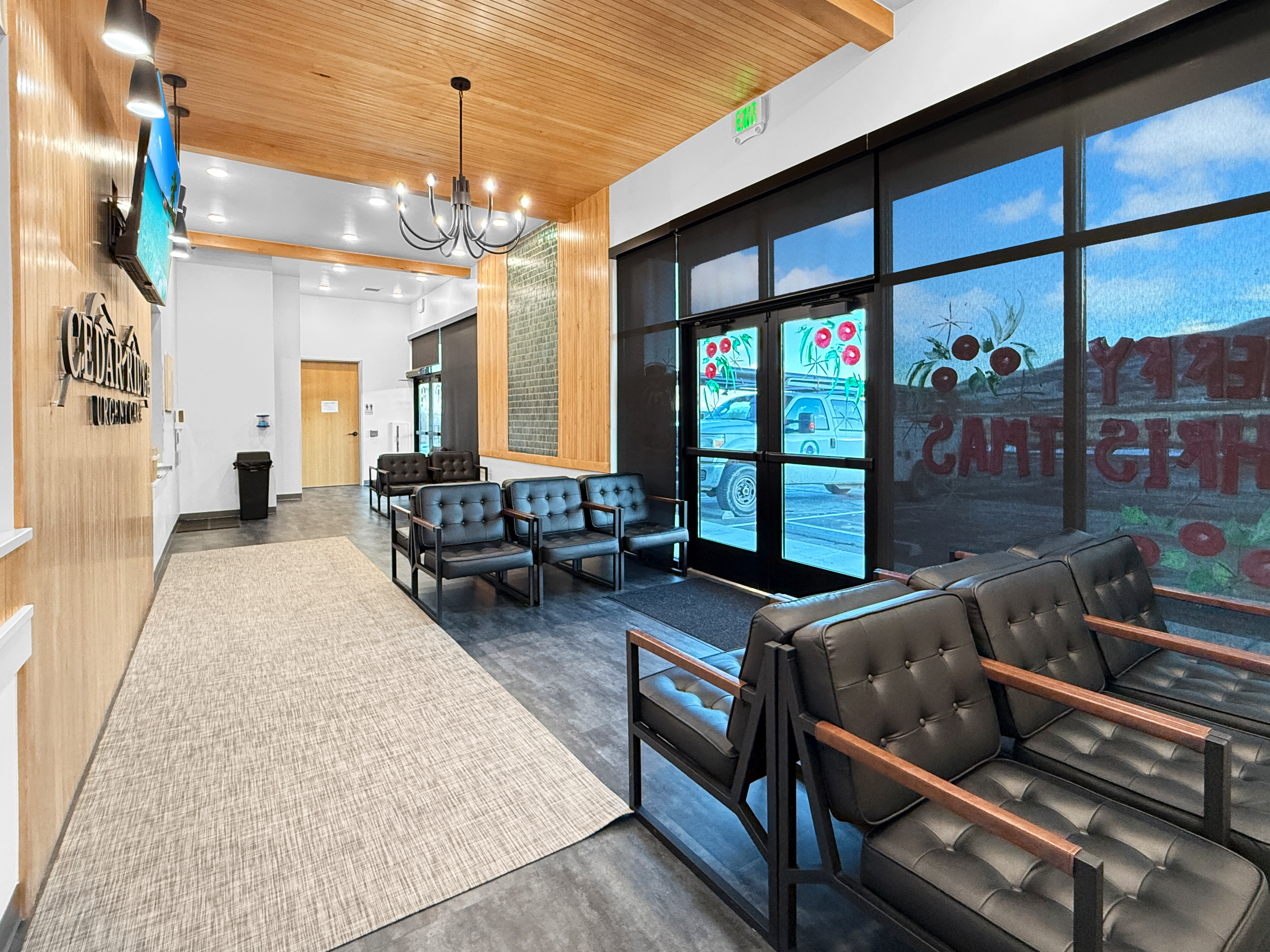 Spacious patient waiting area with custom chandelier, natural wood ceiling beams, runner rug, and modern upholstered chairs
