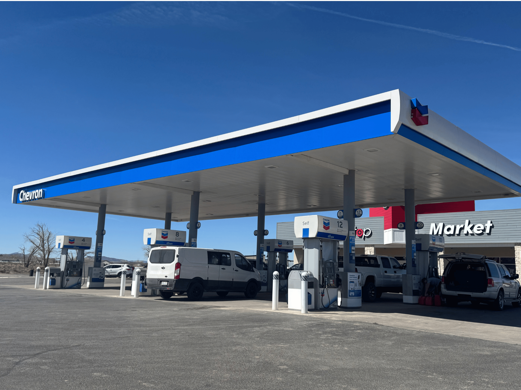 Wide exterior view of Chevron fuel canopy and Foster's Market in Enoch, Utah under a blue sky