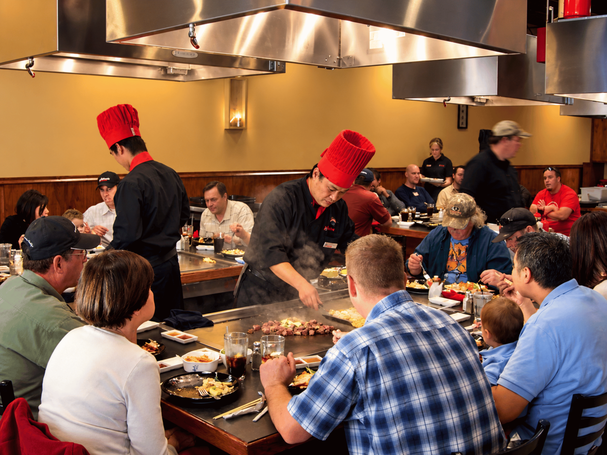 Spacious hibachi dining room with multi-station teppanyaki grills, integrated fire suppression, and seated guests