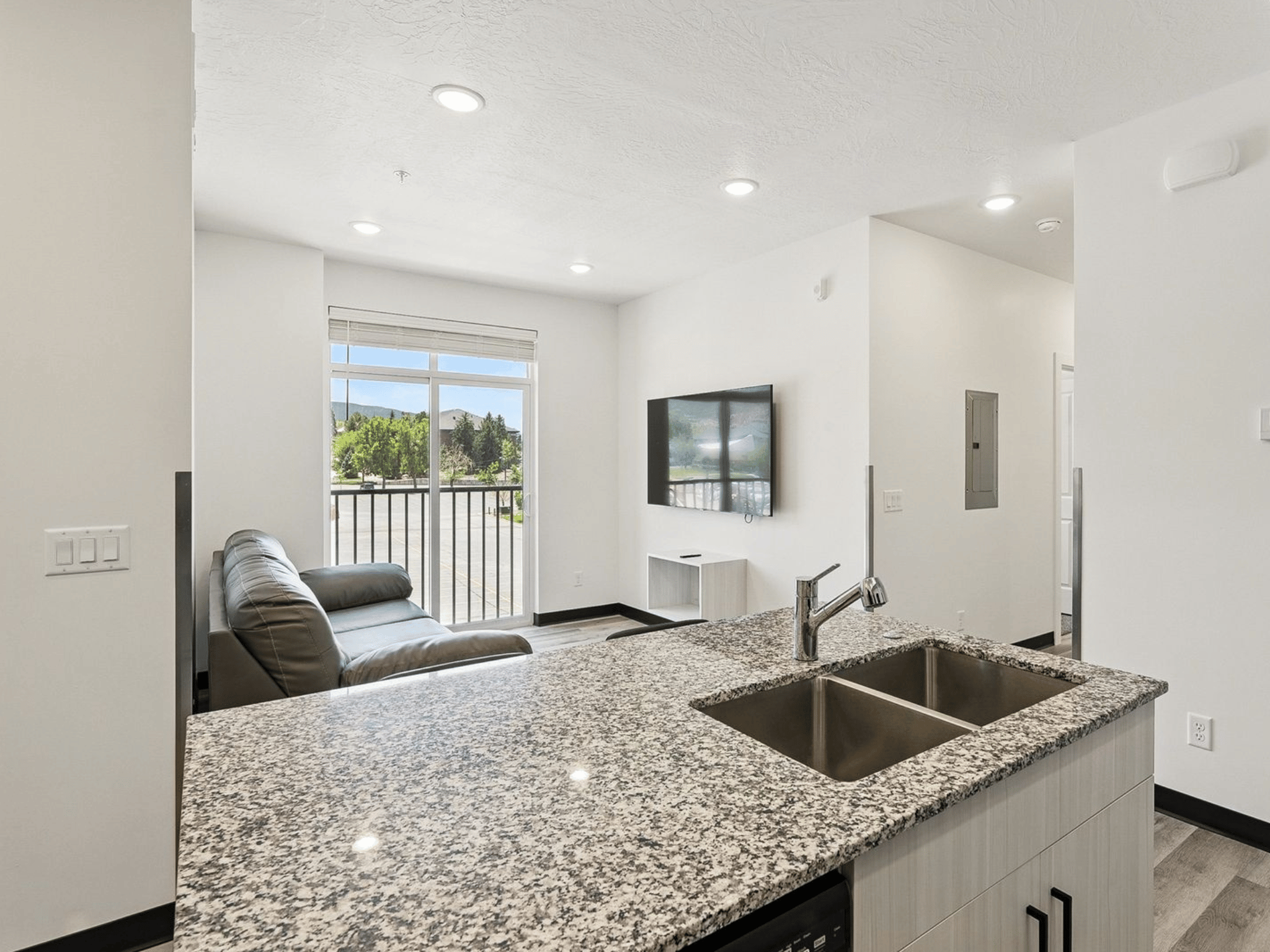 Apartment kitchen island with stainless double sink overlooking living room and patio