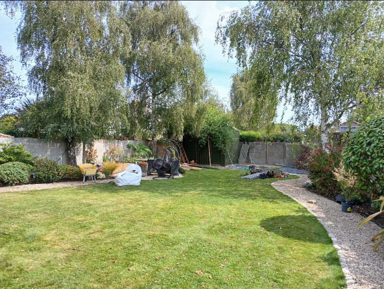 Spacious Dublin South Side garden featuring mature silver birch trees, curved golden gravel pathway, lush green lawn and garden seating.